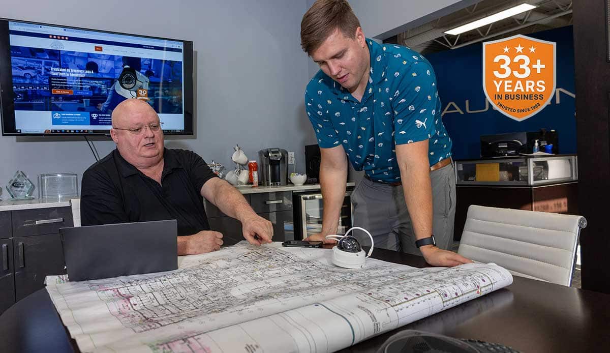 Two men reviewing architectural plans in office.