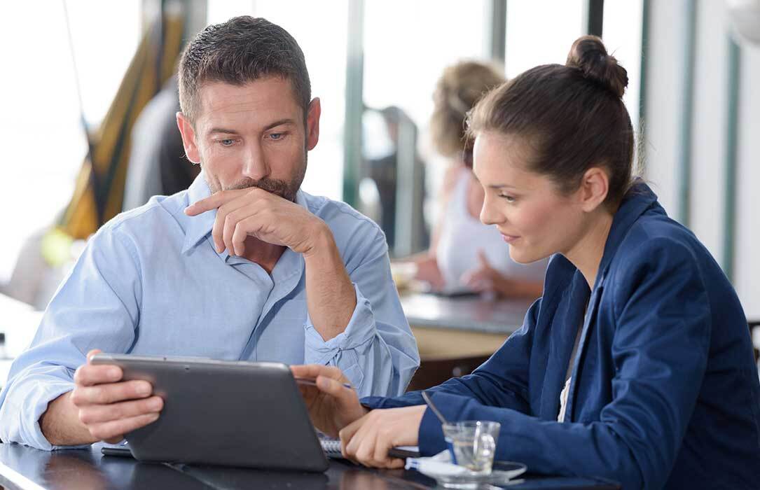 Two professionals discussing business on a tablet.
